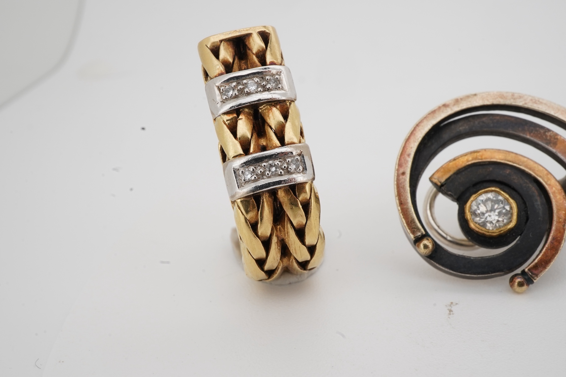 Two pairs of diamond earrings, comprising: one pair of woven design, set with brilliant-cut diamonds totalling approximately 0.10 carats, mounted in bicoloured 18ct gold, length 2.4cm each, post fittings, British hallmar